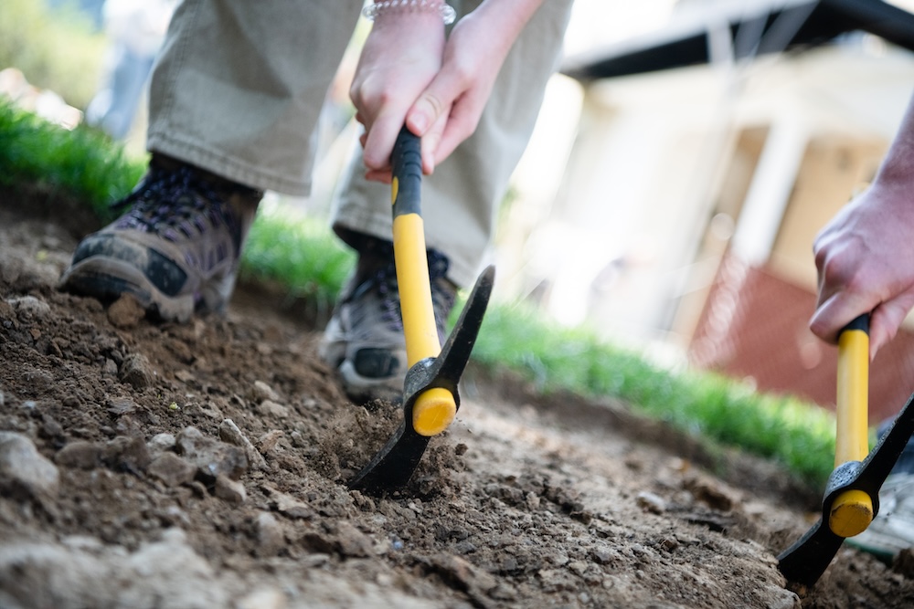 Two pick axes dig into the ground at the Humanities Center