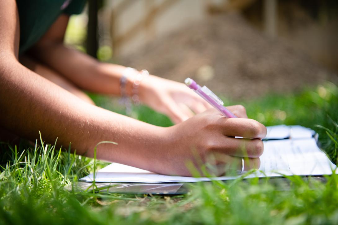 Student writing in grass